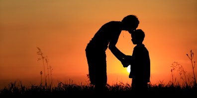 Silhouette of mother kissing child on head